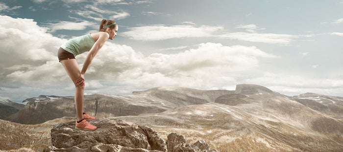 female runner resting on mountaintop