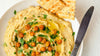 a plate of hummus with pita bread and a butter knife