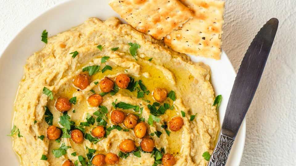 a plate of hummus with pita bread and a butter knife