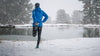 person in warm weather clothes stretching by a lake in the snow