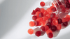 A clear jar tipped over with red and dark red gummy supplements spilling onto a white surface.