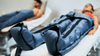 **Alt text:** *Athletes using compression therapy leg sleeves while lying on recovery beds.