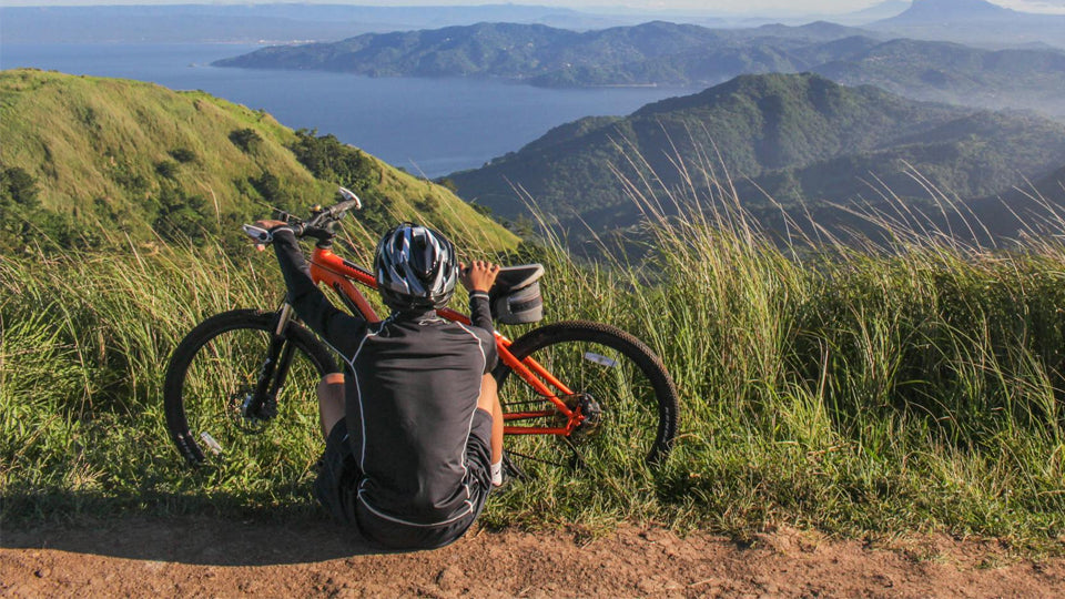 a cyclist on a hill overlooking a gorgeous scene of mountains and a body of water